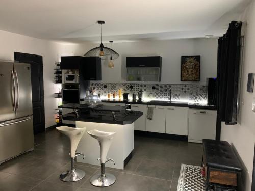 une cuisine avec des armoires noires et blanches et des appareils électroménagers blancs dans l'établissement Maison moderne à Cheval-Blanc, à Cheval-Blanc