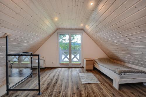 een zolderkamer met een bed en een raam bij Guest House in Lesko
