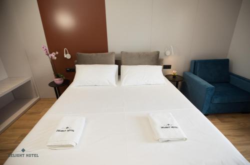a bedroom with a large white bed and a blue chair at Delight Hotel in Ksamil