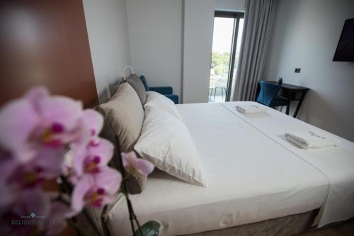 a bedroom with a bed with white sheets and pink flowers at Delight Hotel in Ksamil