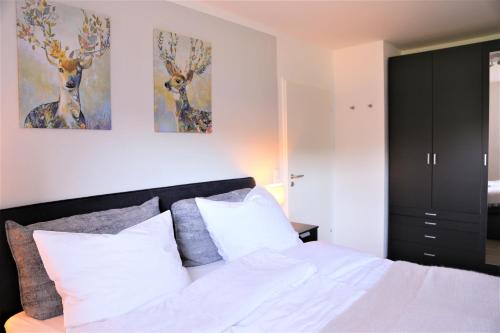 een slaapkamer met een bed en twee schilderijen van herten aan de muur bij Ferienwohnung Berg-Klee in Hahnenklee-Bockswiese