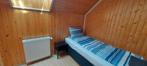 een kleine kamer met een bed in een houten hut bij Gesztenyés Apartmanház Tiszaalpár in Tiszaalpár