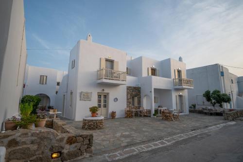 un gran edificio blanco con mesas y sillas en TWINS-TRISA APARTMENTS en Ornos