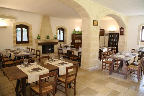 a restaurant with tables and chairs and a fireplace at Masseria Parco di Castro in Montalbano