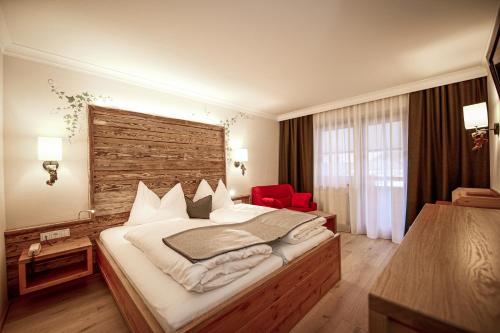 a bedroom with a large bed and a red chair at Hotel Happy Filzmoos in Filzmoos