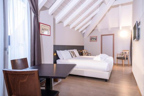 a bedroom with a white bed and a table at Hotel Osteria della Pista dal 1875 in Casorate Sempione