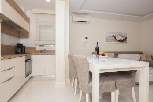 a white kitchen with a white table and chairs at Promajna Leone Erceg Apartments in Promajna