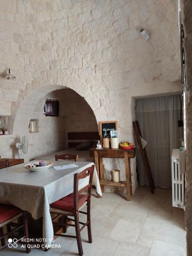 ein Esszimmer mit einem Tisch und einer Steinmauer in der Unterkunft Truly Home Short Lets in Locorotondo