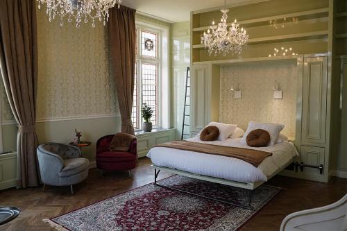 a bedroom with a bed and a chair and a chandelier at Boetiekhotel Ons Oude Raadhuis digitaal inchecken in Hooge Zwaluwe