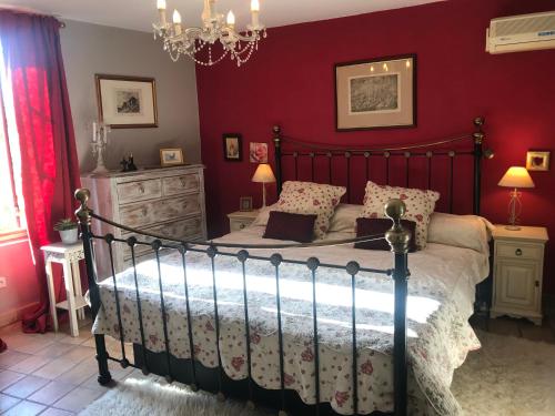 - une chambre avec un lit aux murs rouges dans l'établissement Le Peyrail, à Les Lèves-et-Thoumeyragues