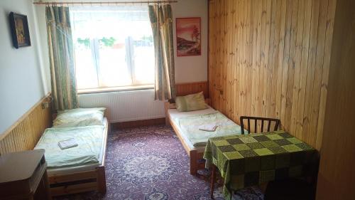 ヤヴォルニークにあるHostinec Na Návsiのベッド2台、テーブル、窓が備わる客室です。