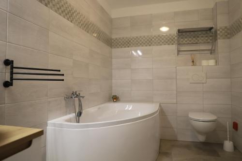 a white bathroom with a tub and a toilet at Rezidencia Podhájska in Podhájska