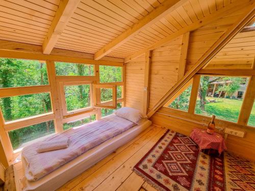 an empty bed in a wooden room with windows at Rajska Rijeka in Foča