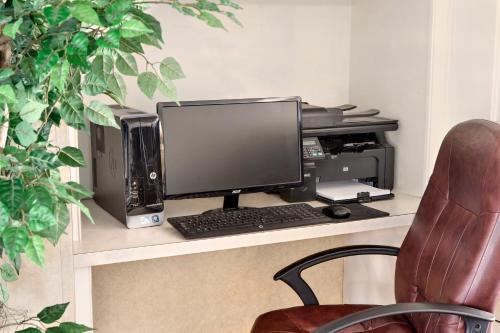 a desk with a computer monitor and a keyboard at Ramada by Wyndham Moses Lake in Moses Lake