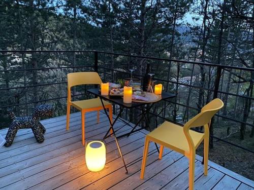 einen Tisch und zwei Stühle auf einer Terrasse mit einem Tisch und zwei Kerzen in der Unterkunft La Parenthèse in Dieulefit