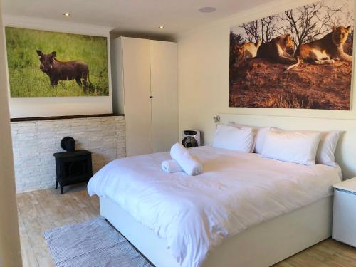 a bedroom with a large white bed with paintings on the wall at theLAB Robertson in Robertson