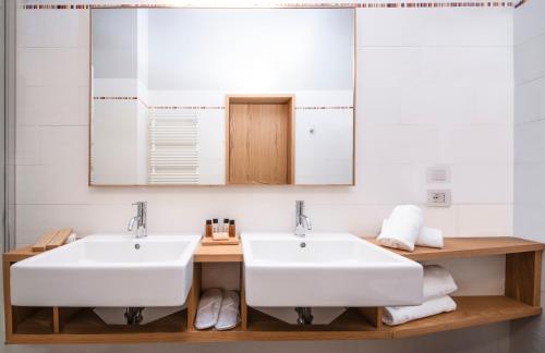 a bathroom with two sinks and a mirror at Hotel Osteria della Pista dal 1875 in Casorate Sempione