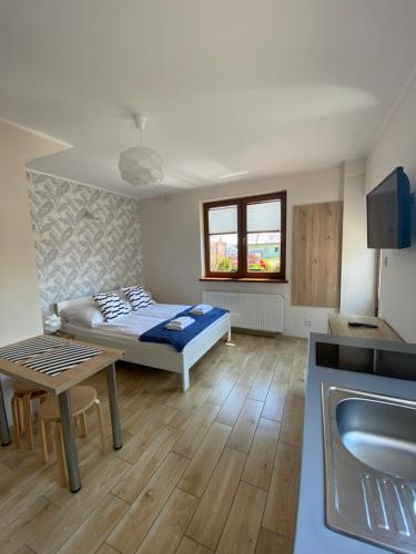 Habitación con cama, mesa y cocina. en Zagaje Pokoje Gościnne en Sarbinowo