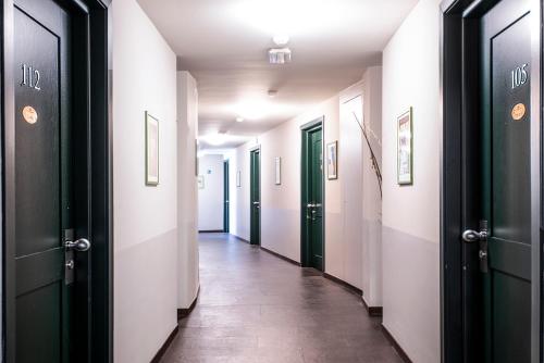 a hallway with green and white doors and a tile floor at Hotel Osteria della Pista dal 1875 in Casorate Sempione