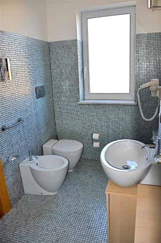 a bathroom with a tub and a toilet and a sink at Hotel Paclà in Avola