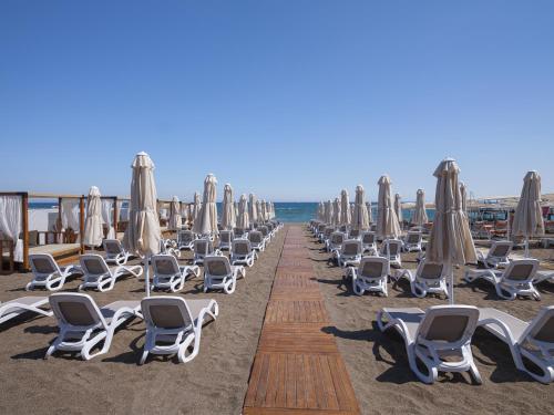 a row of lounge chairs and umbrellas on a beach at Elysium Green Suites in Antalya