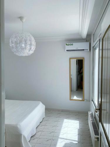 a white bedroom with a bed and a mirror at Roof Top Pied dans l'Eau Panoramic View, 80 meters from Seaside in Hammamet