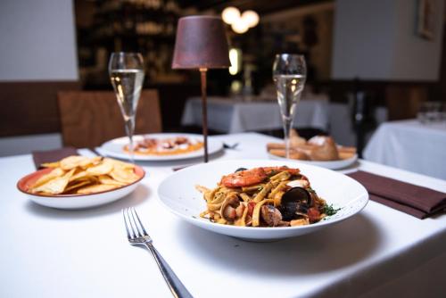 a table with plates of food and glasses of wine at Hotel Osteria della Pista dal 1875 in Casorate Sempione