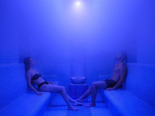 two people sitting on benches in a blue room at Elysium Green Suites in Antalya