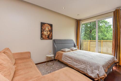 1 dormitorio con cama, sofá y ventana en Sea Apartaments, en Palanga