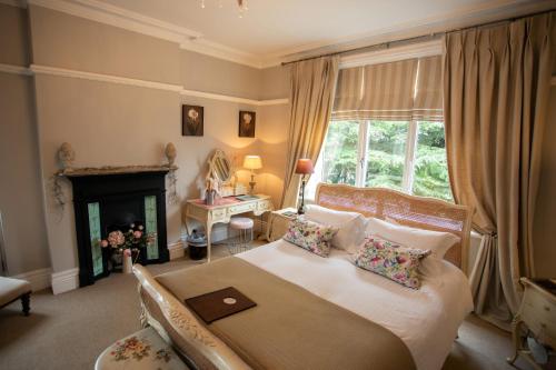 a bedroom with a large bed and a fireplace at Treherne House & The Malvern Retreat in Great Malvern