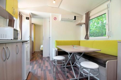 a small kitchen with a table and stools in it at Ideal Camping Lampele GmbH in Ossiach