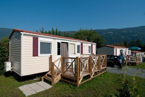 ein kleines weißes, winziges Haus mit einer Veranda in der Unterkunft Ideal Camping Lampele GmbH in Ossiach