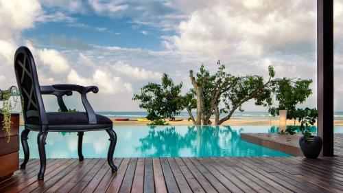 a chair sitting on a deck next to a swimming pool at Essenza Hotel in Jericoacoara