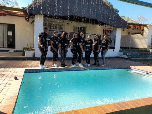 a group of people standing next to a swimming pool at SimbaSun Cottages in Midrand