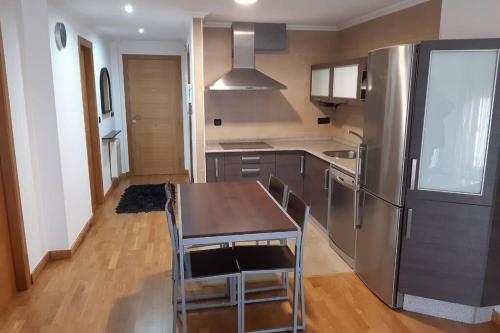 eine Küche mit einem Tisch und einem Kühlschrank aus Edelstahl in der Unterkunft Apartamento en Ribeira a pie de playa (COROSO) in Ribeira