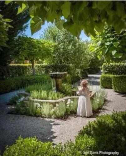 a woman in a white dress sitting in a garden at Howlong Old Post Office Luxury Suite in Howlong