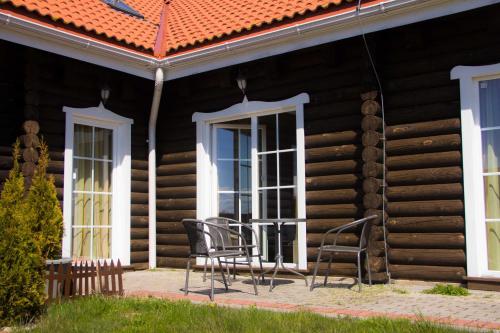 une véranda d'une maison en rondins avec des chaises et une table dans l'établissement Šventosios Ranča, à Šventoji