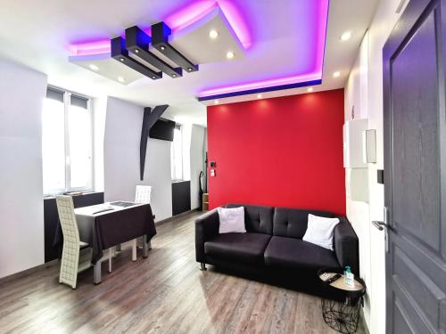 - un salon avec un canapé noir et un mur rouge dans l'établissement Appartement moderne avec balnéothérapie, à Mers-les-Bains