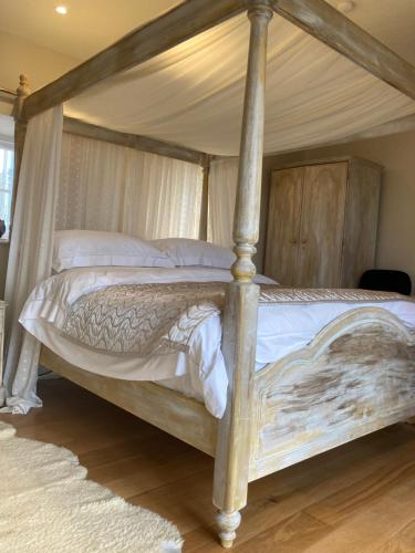 a bedroom with a four poster bed with a canopy at Snowdrop cottage @ Ty-llwyd in Treffynnon 