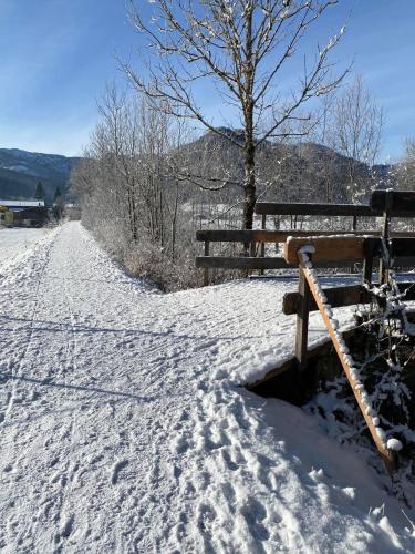 a bench sitting in the snow next to a road at Haus Alpenrose in Waidring