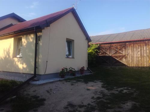 a small white house with a fence and some plants at Zaciszny Zakątek in Drohiczyn nad Bugiem