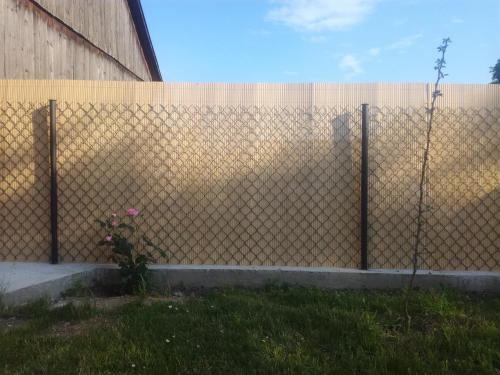 a fence in front of a building with some flowers at Zaciszny Zakątek in Drohiczyn nad Bugiem