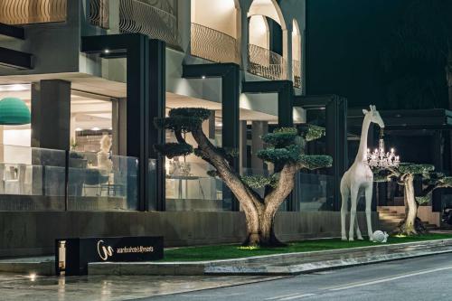a statue of a giraffe and trees in front of a building at Hotel Cerere in Paestum