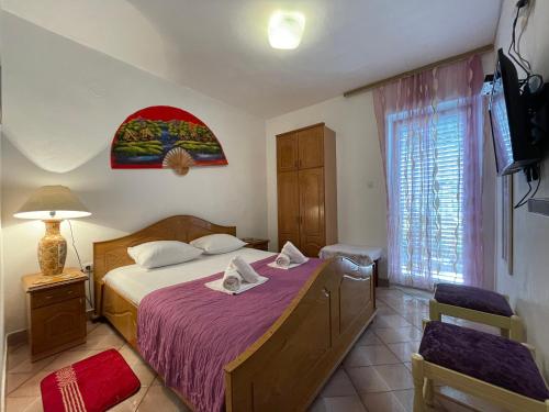sypialnia z łóżkiem, telewizorem i oknem w obiekcie Apartments Marković w Budvie