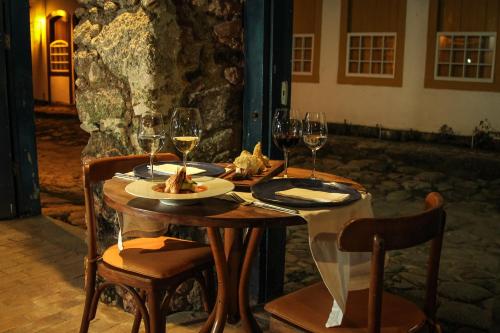 a wooden table with wine glasses and food on it at Pousada Bartholomeu in Paraty