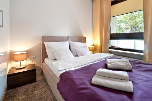 a bedroom with a purple bed with two towels on it at P&O Giełdowa Serviced Apartments in Warsaw