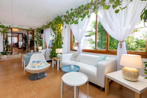 a living room with a couch and tables and windows at Hostal Manolita in San Antonio