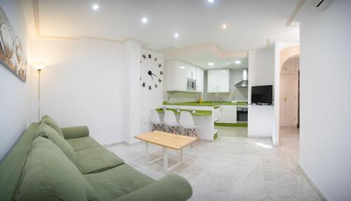 a living room with a green couch and a kitchen at Caminito del Falla I Ha Apartment in Cádiz