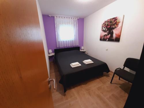 a small bedroom with a black bed and a window at Apartment Luna in Trogir