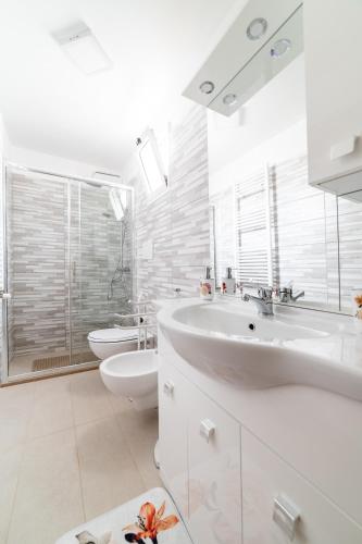 a white bathroom with a sink and a toilet at Palazzo Fiordaliso - Puglia Mia Apartments in Monopoli